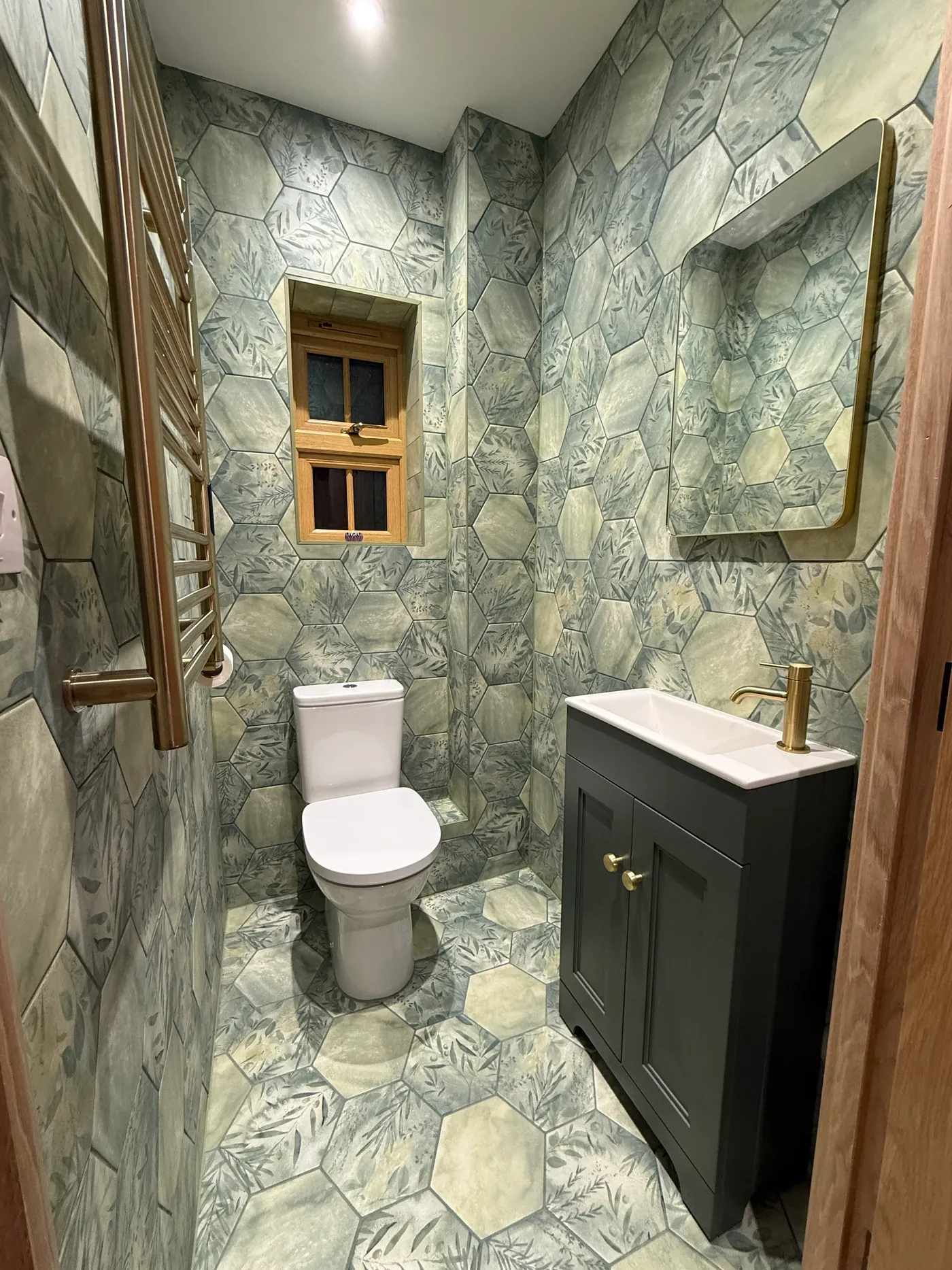 Bathroom renovation with sage green hexagonal tiles and brass fittings