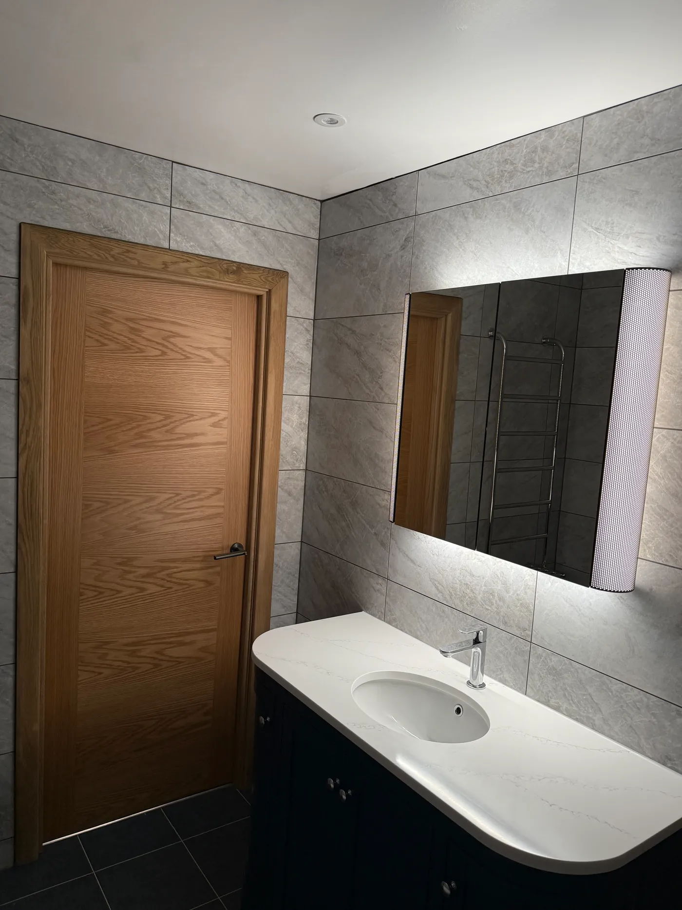 Bathroom vanity with marble worktop, oval basin and backlit mirror