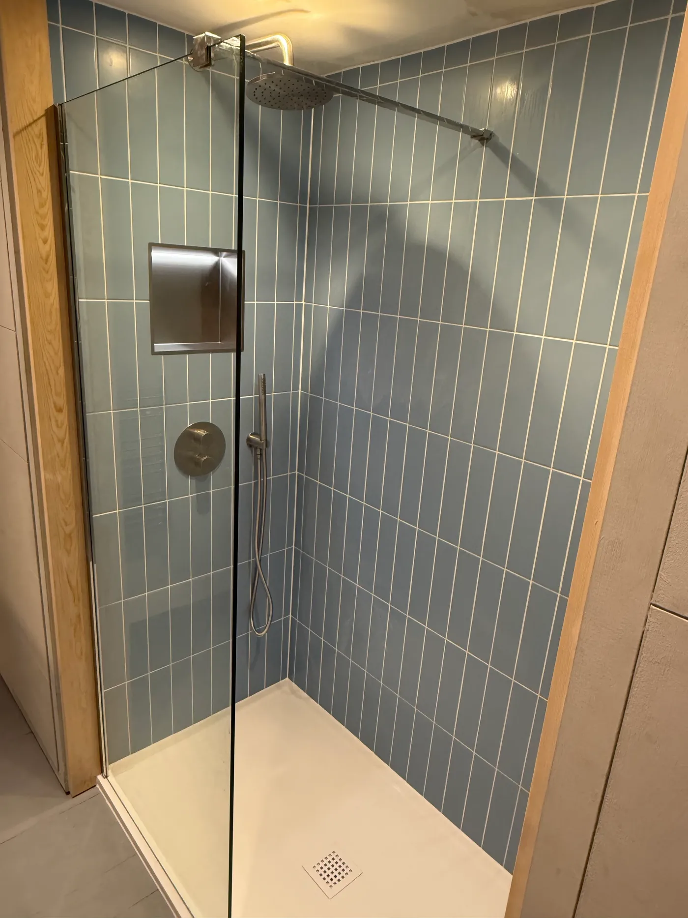 Walk-in shower with blue subway tiles and chrome rainfall shower